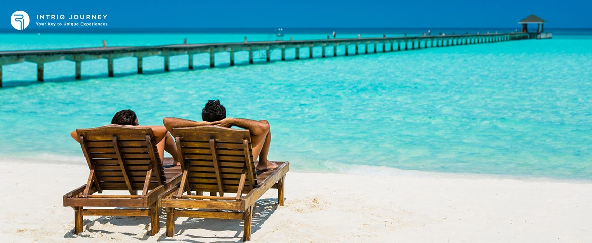 A couple relaxing on wooden beach chairs by the ocean