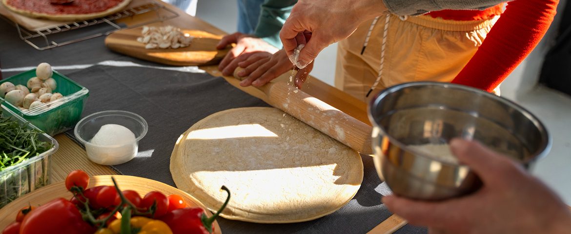 Family preparing handmade pizza during a private Italian cooking class.