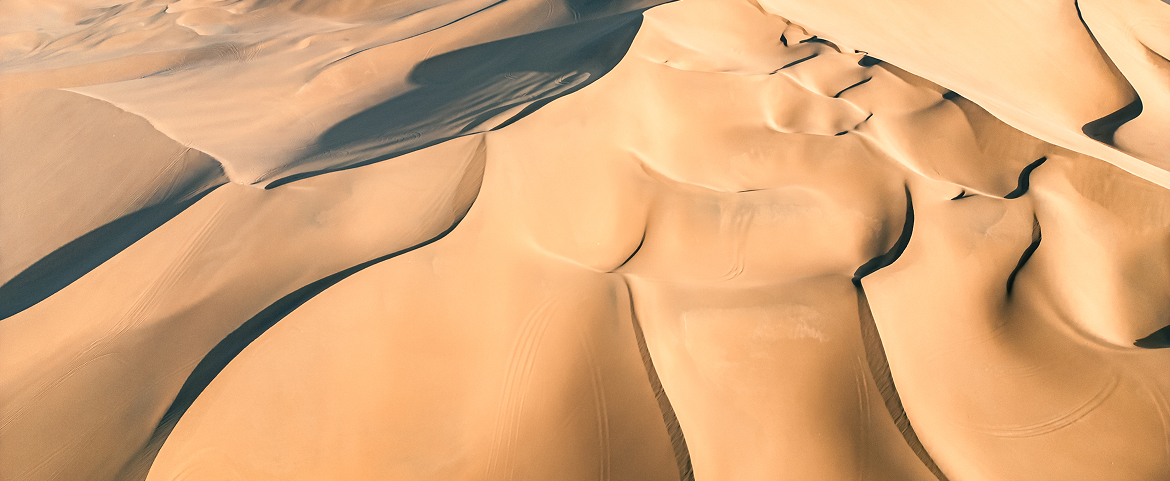 Golden sand dunes of the Taklamakan Desert under sunlight.