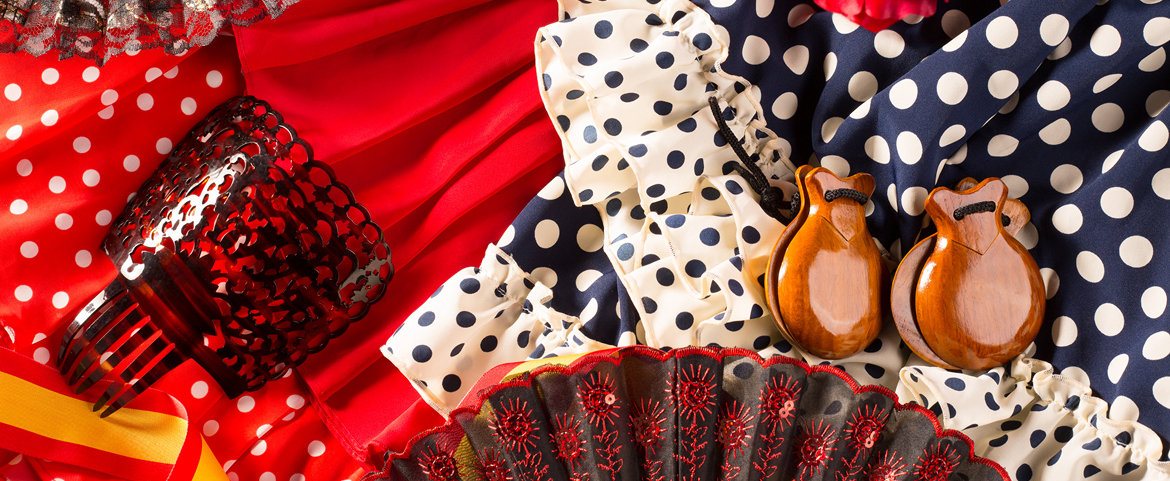 Traditional flamenco attire with castanets, red rose, and fans.