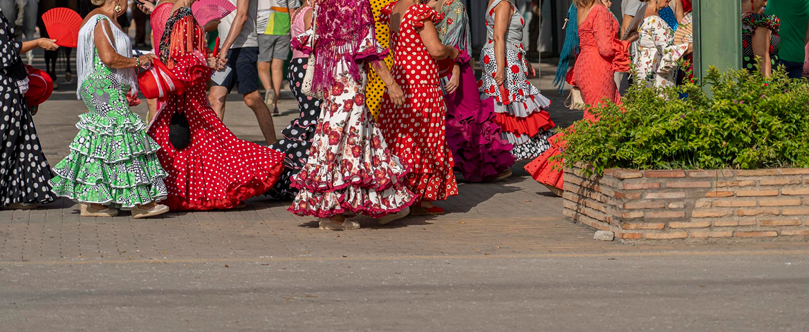Women wearing colorful polka dot flamenco dresses at Spanish festival.